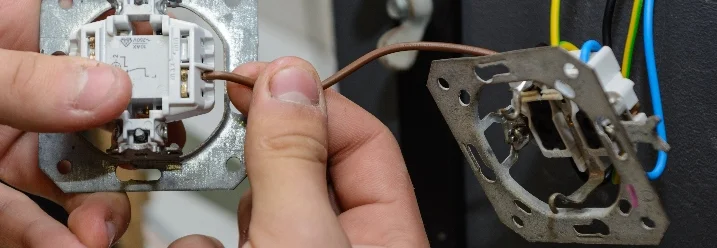 Person verbindet Kabel mit Lichtschalter